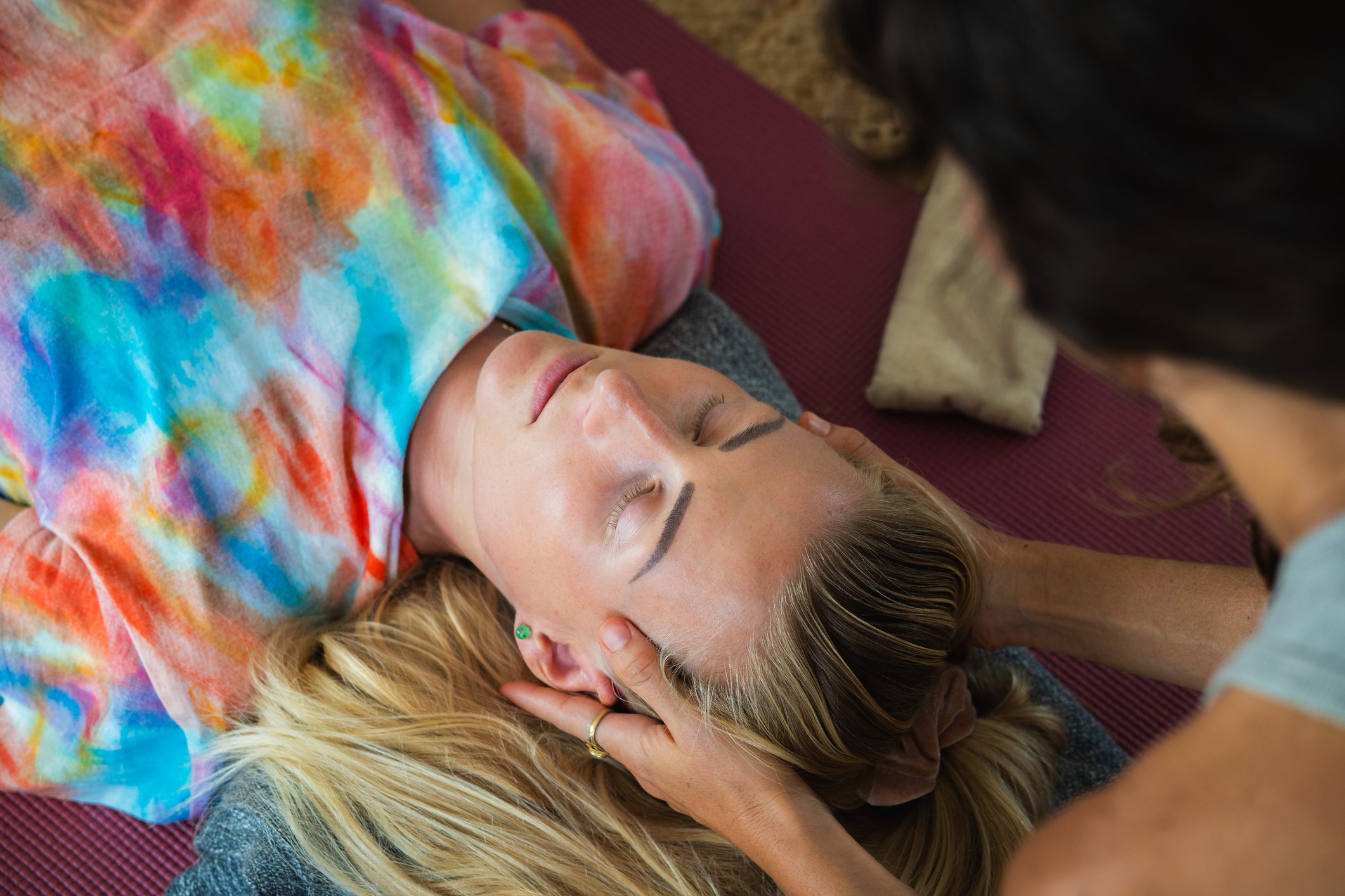 Therapist is using craniosacral therapy techniques on a patient lying down with her eyes closed